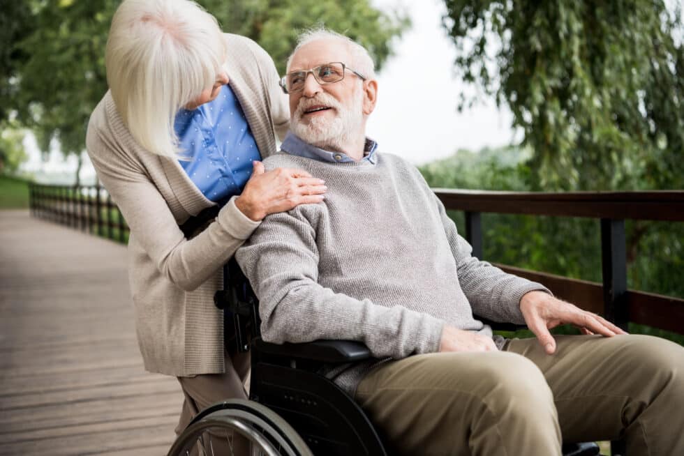 A woman conversing with an elderly man in a wheelchair.