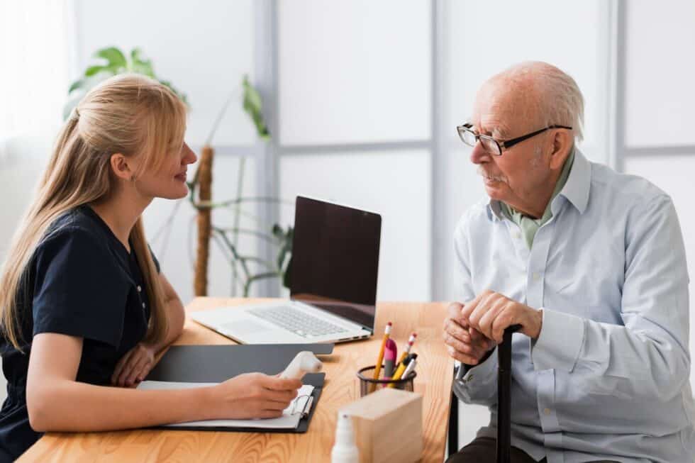 A woman conversing with an elderly man at a desk.