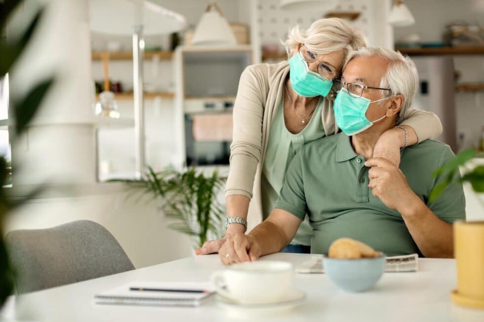 An elderly couple wearing face masks while staying safe at home during the pandemic.