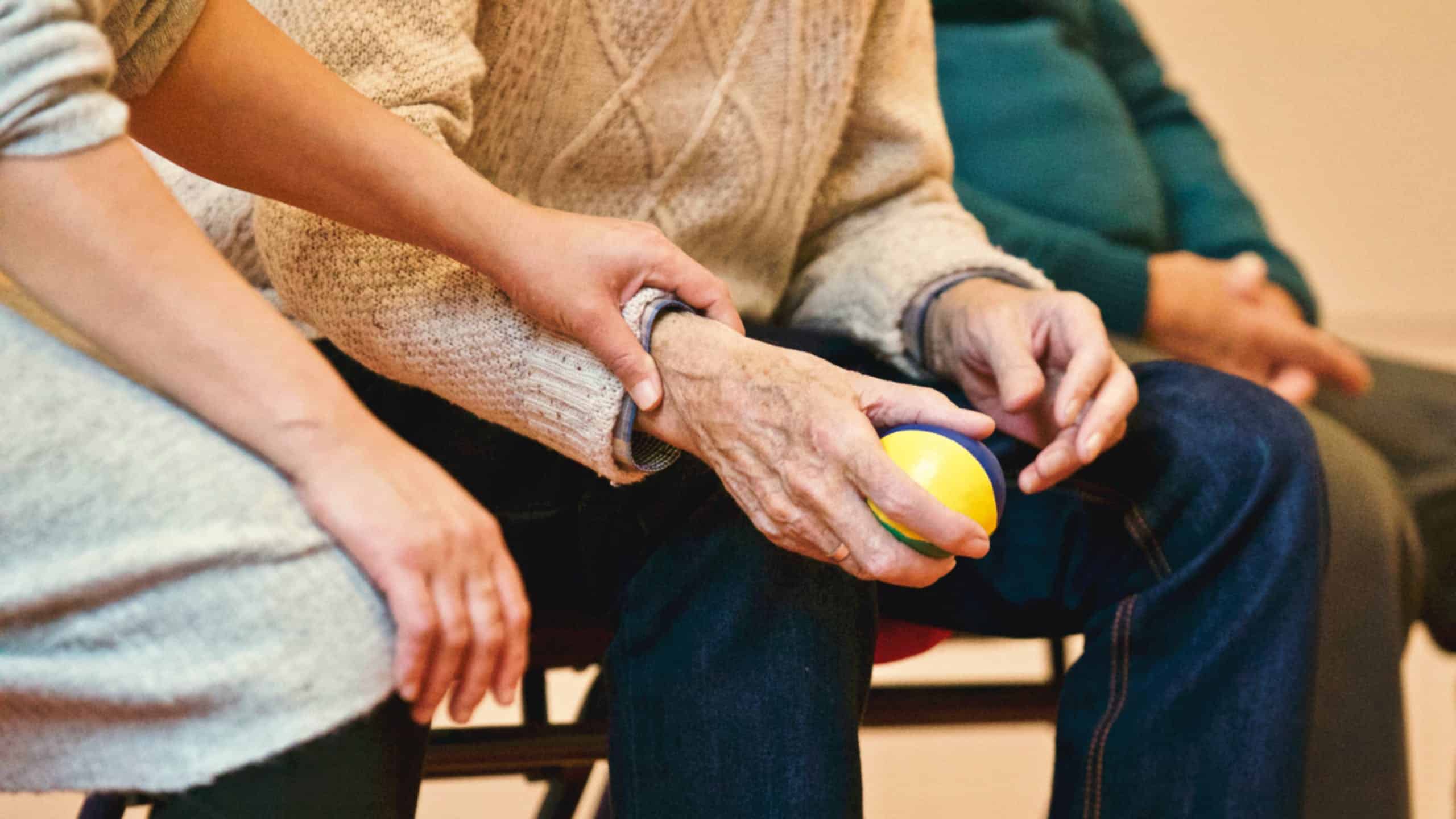 A group of elderly people sitting in chairs with a ball in their hands.