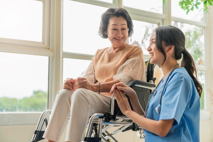 Caregiver providing elder care assistance with a senior woman in a wheelchair.