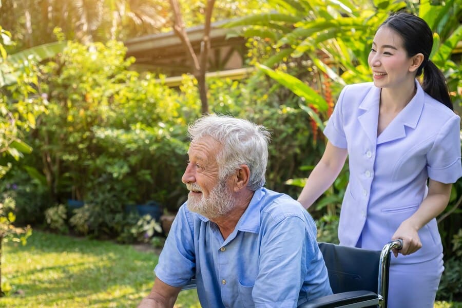 happy nurse providing always best care solution for elderly man in a wheelchair